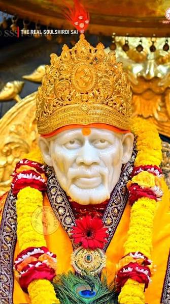 Sai Baba murti decorated with saffron robes and marigold garlands during aarti in Shirdi